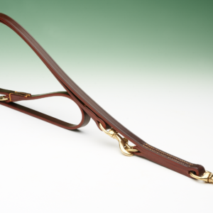 A brown leather dog lead, lies on a white surface, curving gently; it features brass hardware.